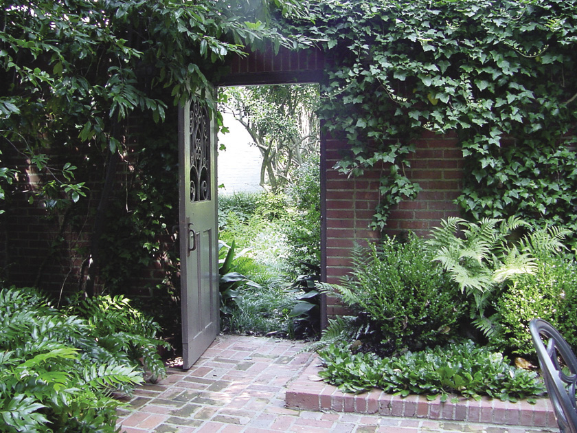 A brick patio area with an open door leading into a separate garden area.